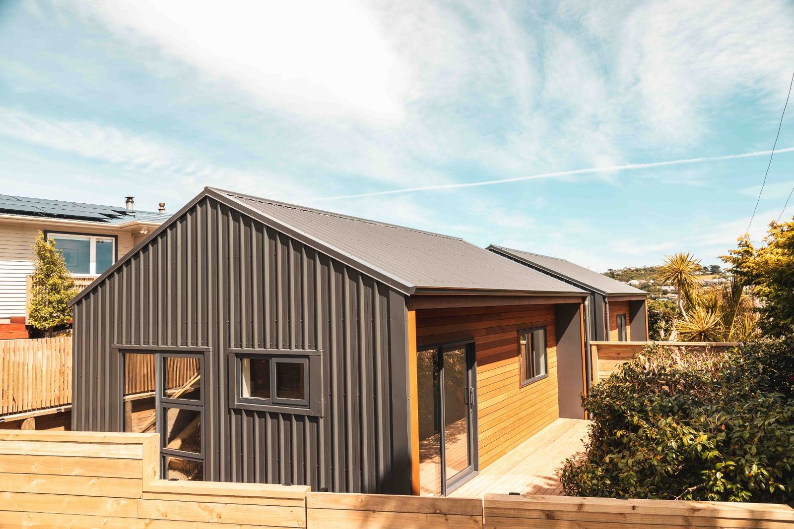 A 38sqm unit surrounded by foliage, large windows inset amongst cedar cladding reflecting the blue sky